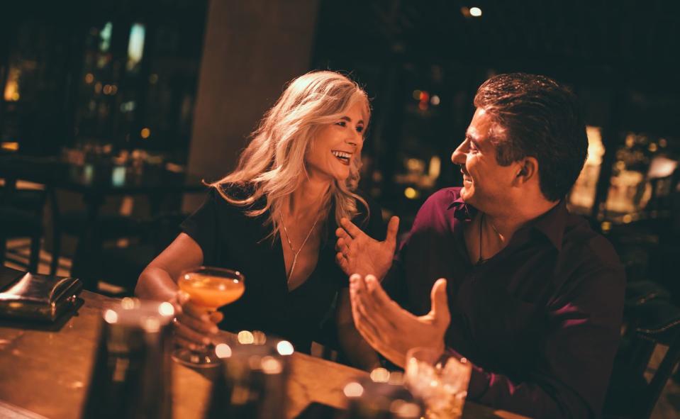 senior husband and wife laughing and having drinks at bar