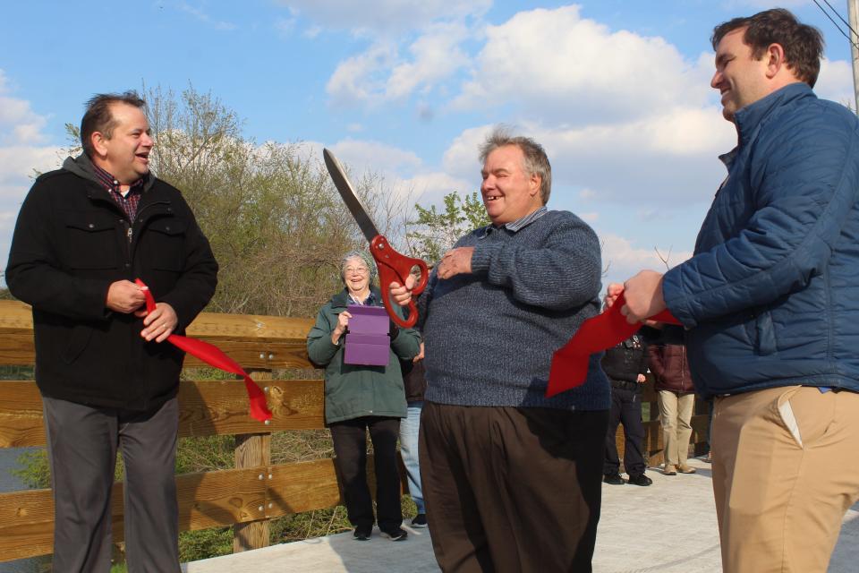 Elmore Village Council President Thomas Jackson,  left, Elmore Mayor Rick Claar and Genoa Mayor Thomas Bergman cut a ribbon to dedicate the new Elmore-to-Genoa extension of the North Coast Inland Bike Trail. Claar died at the age of 66 on Monday, Nov. 29.