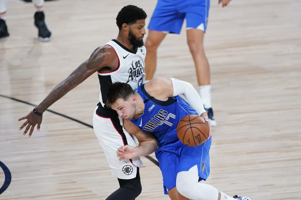 Dallas Mavericks' Luka Doncic (77) drives against Los Angeles Clippers' Paul George (13) during the first half of an NBA basketball first round playoff game Friday, Aug. 21, 2020, in Lake Buena Vista, Fla. (AP Photo/Ashley Landis, Pool)