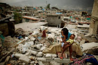 <p>Sherider Anilus, 28, and her daughter, 9-month-old Monica, sit on the spot where her home collapsed during the Jan. 12 earthquake in the Fort National neighborhood Feb. 26, 2010 in Port-au-Prince, Haiti. Living in a shack with her husband and two children, Anilus returned to Fort National from a tent camp in downtown Port-au-Prince so to escape the flash flooding that happens when it rains. (Photo: Chip Somodevilla/Getty Images) </p>