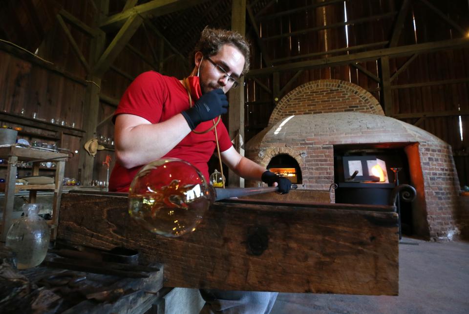 Preston Sheeks, glass blower at Hale Farm & Village works on creating a WitchÕs Ball ornament on his bench before putting the ornament back into the newly renovated glass blowing furnace on Friday Sept. 19, 2020 in Akron. The furnace is housed in a brick enclosure that replicates a wood burning furnace which would be the type of furnace used in the mid 19th century.  [Mike Cardew/Beacon Journal]