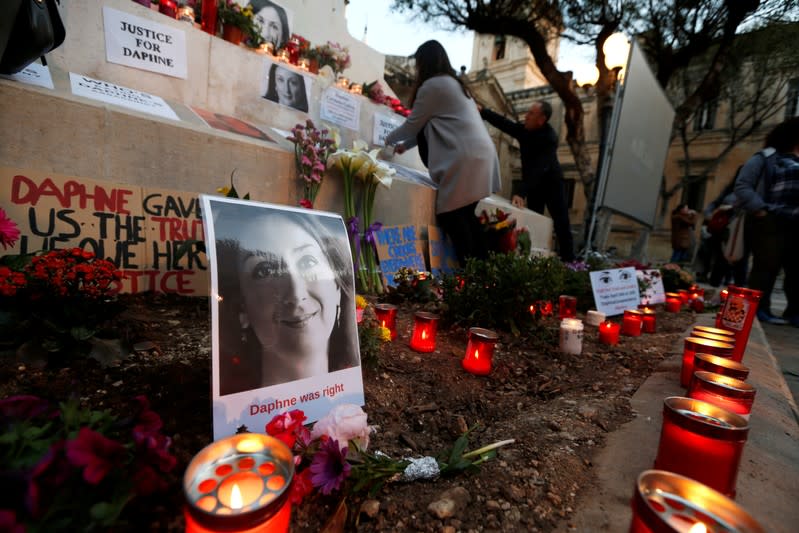 People light candles and place flowers on a makeshift memorial during a protest and vigil marking eighteen months since the assassination of anti-corruption journalist Daphne Caruana Galizia outside the Courts of Justice in Valletta