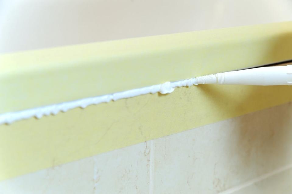 Applyying uneven caulking along bathroom tile edges