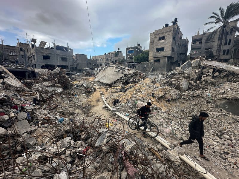 Palestinians inspect houses, destroyed in Israeli strikes during the conflict, at Khan Younis refugee camp