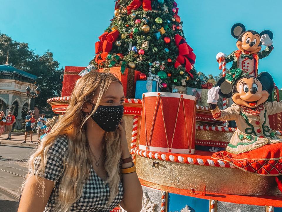 kayleigh in front of a holiday parade float with mickey and minnie at disney world magic kingdom