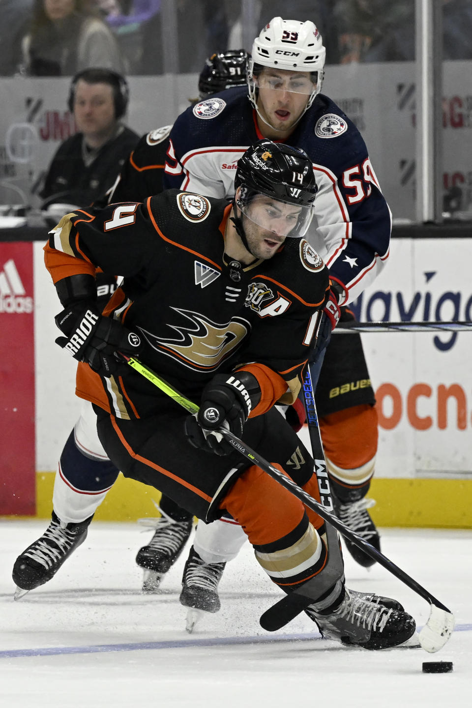 Anaheim Ducks center Adam Henrique (14) controls the puck past Columbus Blue Jackets right wing Yegor Chinakhov (59) during the second period of an NHL hockey game in Anaheim, Calif., Wednesday, Feb. 21, 2024. (AP Photo/Alex Gallardo)