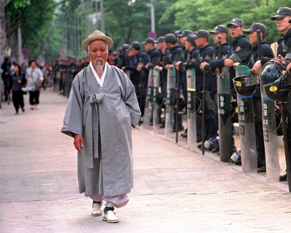 FILE - In this Thursday, May 28, 1998. file photo an elderly man wearing traditional Korean costumes walks past a police line as workers stage an anti-government rally calling for job security, at Chongmyo Park in Seoul, South Korea While most people born in rich countries will live longer by 2030 with women in South Korea estimated to reach at least 91. Americans will have among the lowest life expectancy of any developed country, a new study predicts (AP Photo/Ahn Young-joonm, File)