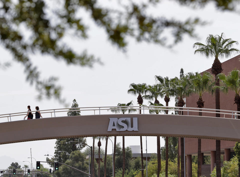 FILE - In this July 25, 2018, file photo, pedestrians cross over University Avenue on the campus of Arizona State University in Tempe, Ariz. As concerns about China’s virus outbreak spread, universities all over the world are scrambling to assess the risks to their programs. One diagnosis was confirmed at ASU and another at the University of Massachusetts at Boston, which said the infected student had recently traveled to Wuhan. (AP Photo/Matt York, File)