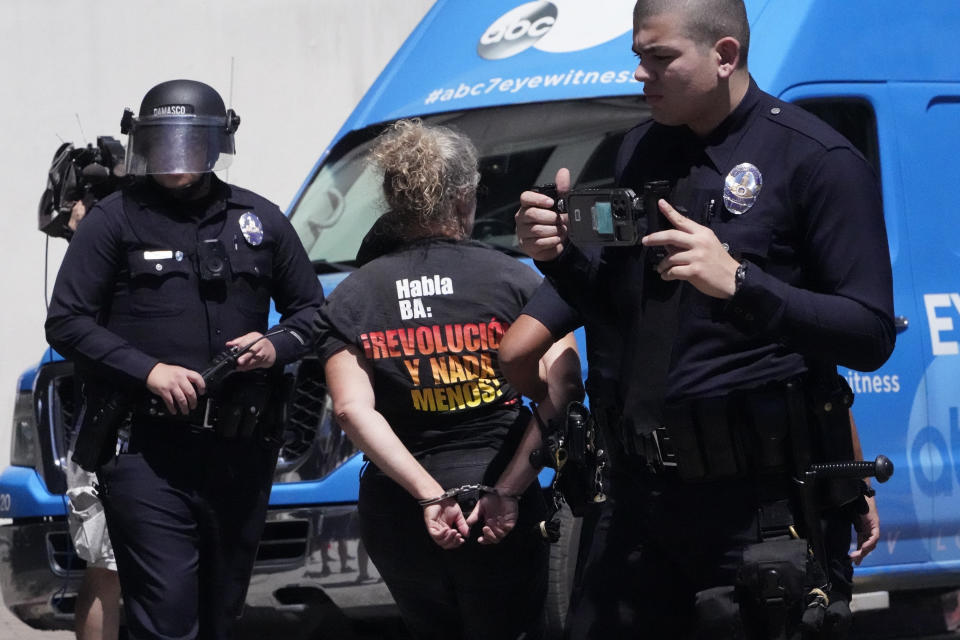 A person is detained by LAPD officers following a surge from police attempting to move a small group of LGBTQ demonstrators away from a Parents Rights sponsored protest nearby Los Angeles Unified School District headquarters, Tuesday, Aug. 22, 2023, in Los Angeles. (AP Photo/Damian Dovarganes)