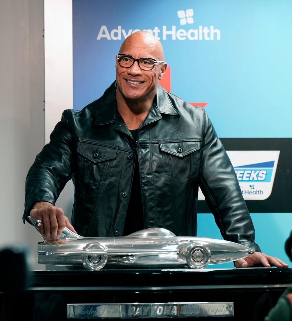 Daytona 500 Grand Marshall Dwayne "The Rock" Johnson poses next to the Harley J. Earl trophy during a press conference at Daytona International Speedway, Sunday, Feb. 18, 2024.