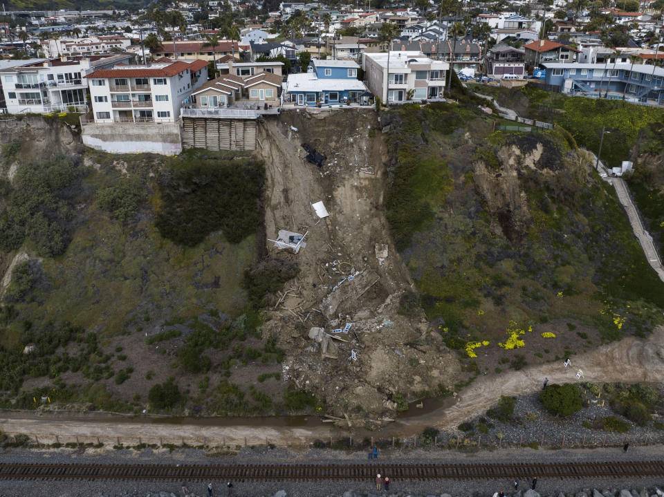 In this image taken with a drone, a mass of debris is seen along a cliff beneath residential homes after a landslide occurred in San Clemente, Calif., Thursday, March 16, 2023. . (AP Photo/Jae C. Hong)