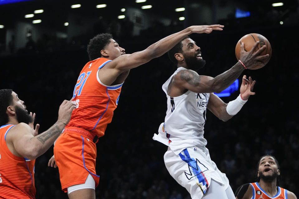 Brooklyn Nets' Kyrie Irving, front right, drives past Oklahoma City Thunder's Kenrich Williams, left, and Aaron Wiggins, center, during the first half of an NBA basketball game Sunday, Jan. 15, 2023, in New York. (AP Photo/Frank Franklin II)
