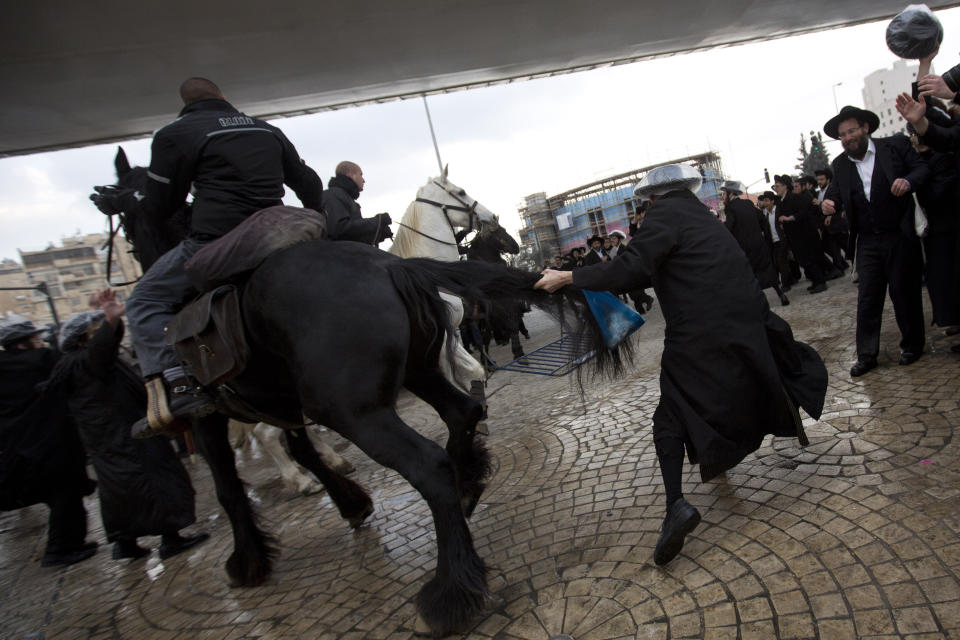 Israeli police officers on horses disperse a crowd of ultra-Orthodox Jewish men during a demonstration in Jerusalem, Thursday, Feb. 6, 2014. Israeli police said thousands of ultra-Orthodox Jews are blocking highways across the country to protest plans to enlist them into the military. (AP Photo/Sebastian Scheiner)