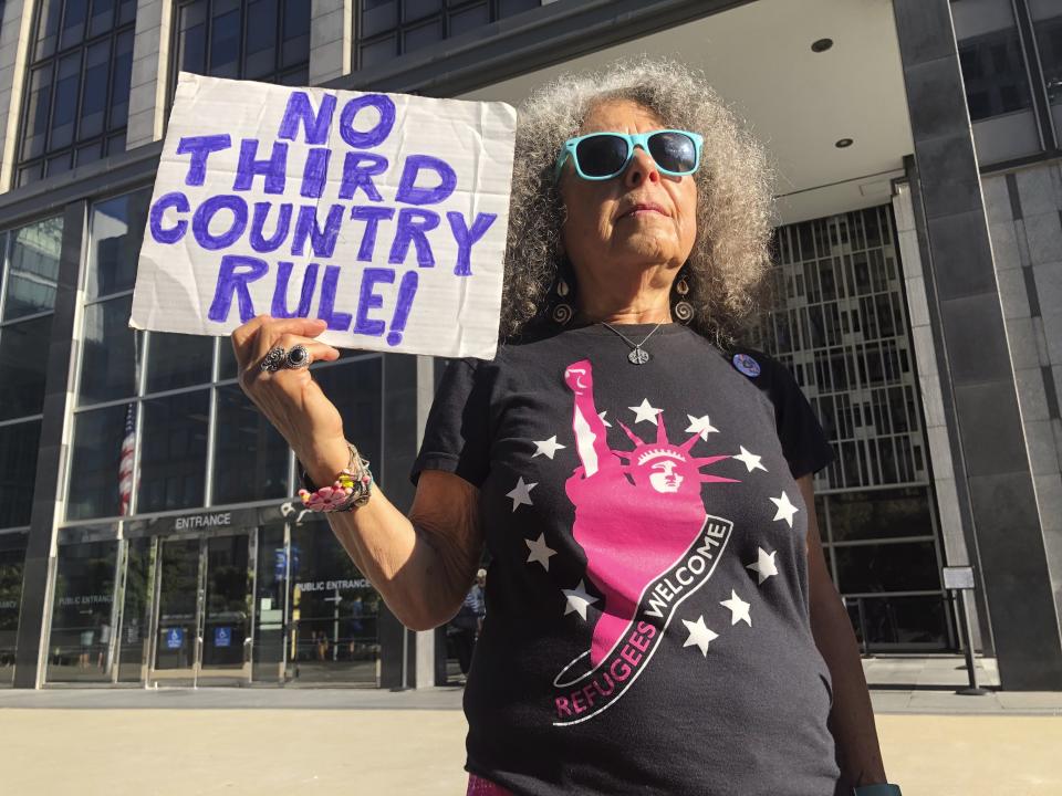 Arla Ertz, holds a protest sign outside of the San Francisco Federal Courthouse on Wednesday, July 24, 2019 in San Francisco, Calif. A federal judge said Wednesday that the Trump administration can enforce its new restrictions on asylum for people crossing the U.S.-Mexico border while lawsuits challenging the policy play out. (AP Photo/Haven Daley)