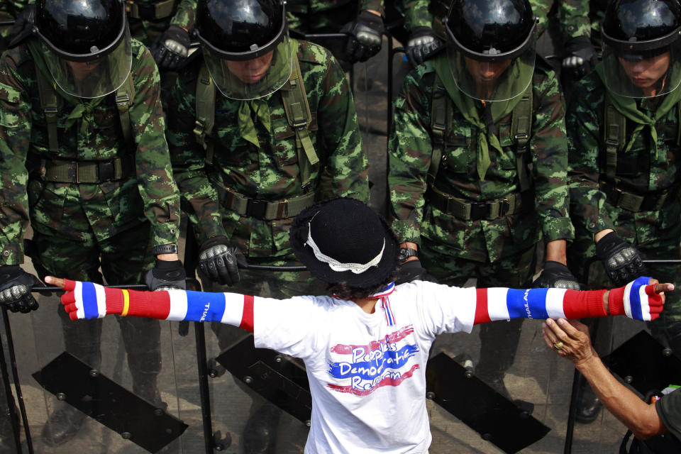 A Thai anti-government protester talks with soldiers guarding the office of Permanent Secretary for Defense, a temporary office of Prime Minister Yingluck Shinawatra on the outskirts of Bangkok, Thailand Wednesday, Feb. 19, 2014. Thousands of Thai anti-government protesters surrounded the prime minister's temporary office in Bangkok's northern outskirts to demand her resignation Wednesday, a day after clashes with riot police left at least five people dead.(AP Photo/Wason Wanichakorn)