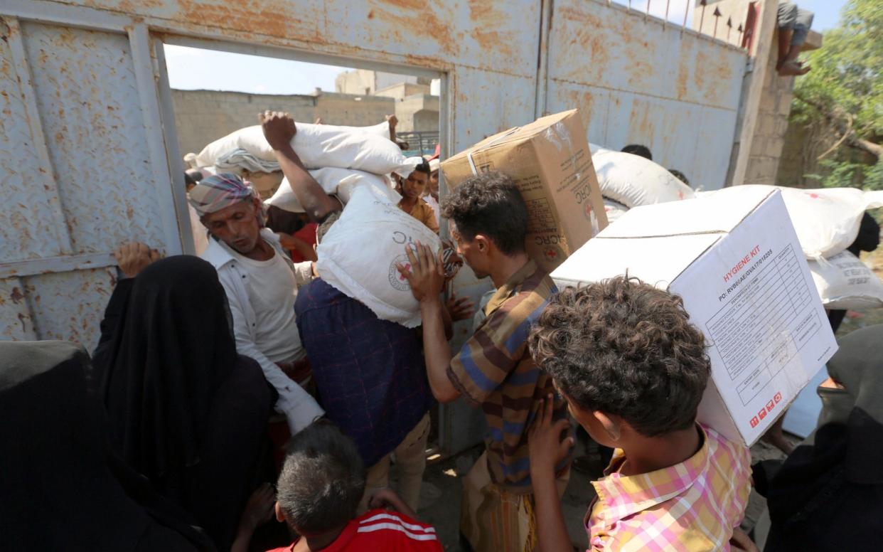 Internally displaced people carry food aid they received in Bajil - REUTERS
