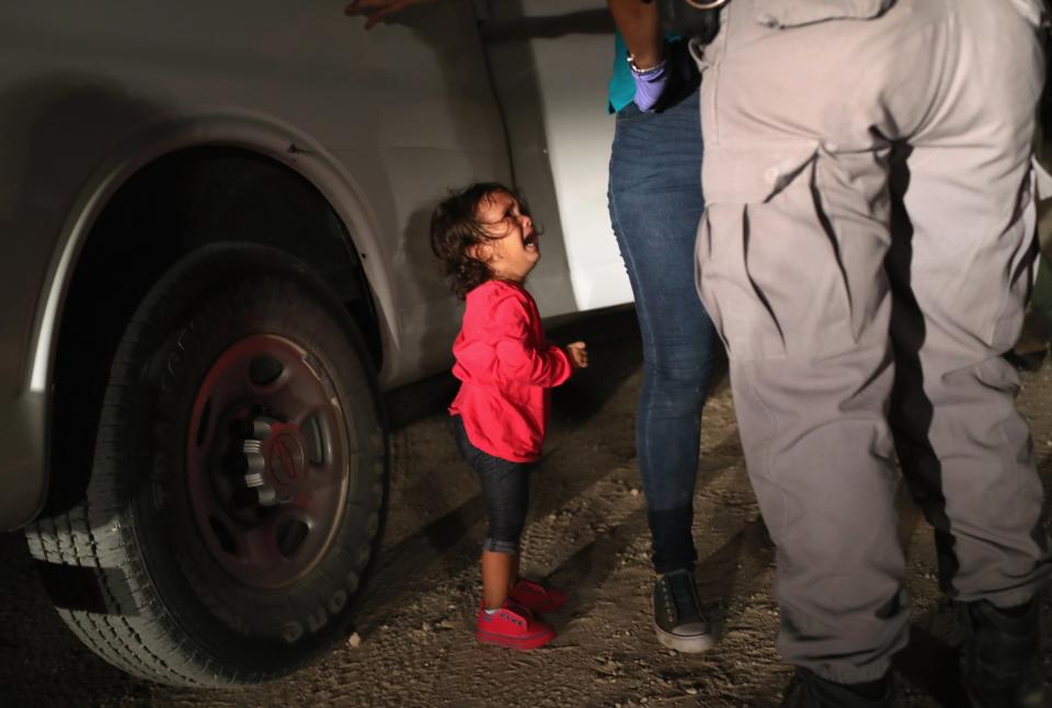 A two-year-old Honduran asylum seeker cries as her mother is searched and detained near the US-Mexico border: Getty Images