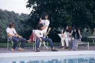 <p>Eric Clapton (center, seated) debates how to make the "peace" sign with John Lennon and Yoko Ono at a pool in 1969.</p>