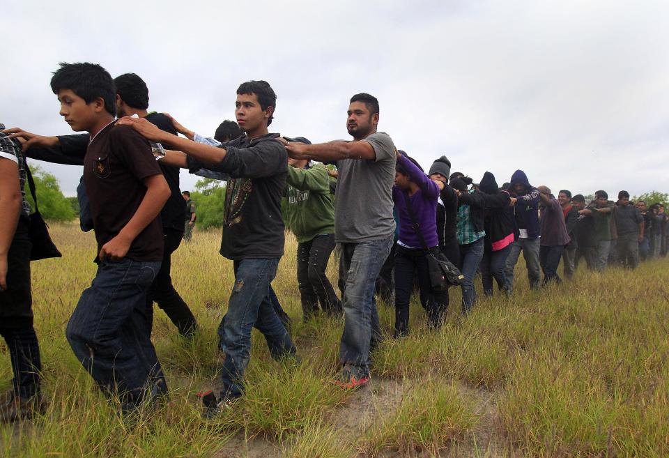 Immigrants suspected of being in the country illegally are transported to a bus after U.S. Border Patrol agents detained about 75 immigrants who'd been living in hut for several days in a brushy area Thursday April 17, 2014 near North 10 St. and Sprague St. in McAllen, Texas. Agents spent about three hours rounding up the immigrants suspected of being in the country illegally after they responded to the area. Most of the immigrants are believed to be from Central America. (AP Photo/The Monitor, Gabe Hernandez)