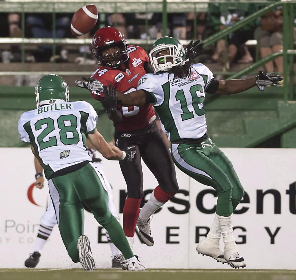 Saskatchewan Roughriders defensive back Eddie Russ (right) intercepts a pass intended for Calgary Stampeders receiver Landan Talley while Craig Butler looks on during the second half of CFL pre-season football action in Regina, Sask., Friday, June 22, 2012. The Stamps defeated the Riders 33-31. THE CANADIAN PRESS/Liam Richards