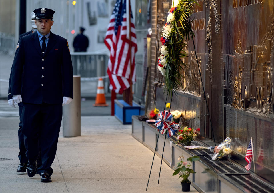 New York City firefighters take a position in front of a memorial on the side of a firehouse adjacent to One World Trade Center and the 9/11 Memorial site during ceremonies commemorating the 18th anniversary of the 9/11 terrorist attacks in New York on Wednesday, Sept. 11, 2019. (AP Photo/Craig Ruttle)