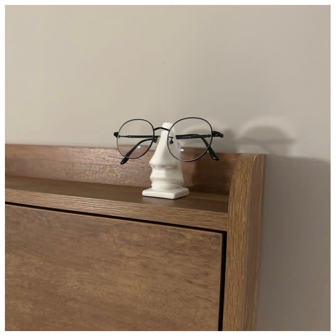 Glasses displayed on a small white bust on a wooden shelf