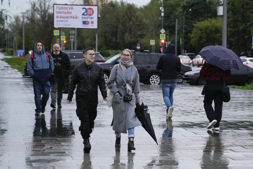 Alyona Popova, the democratic Yabloko party candidate for the State Duma, center, walks in a street before a meeting with voters in Moscow, Russia, Friday, Sept. 3, 2021. Popova is running in a Moscow district, and her competitors include a famous TV personality widely seen as pro-government and a seasoned lawmaker from the Communist Party. (AP Photo/Pavel Golovkin)
