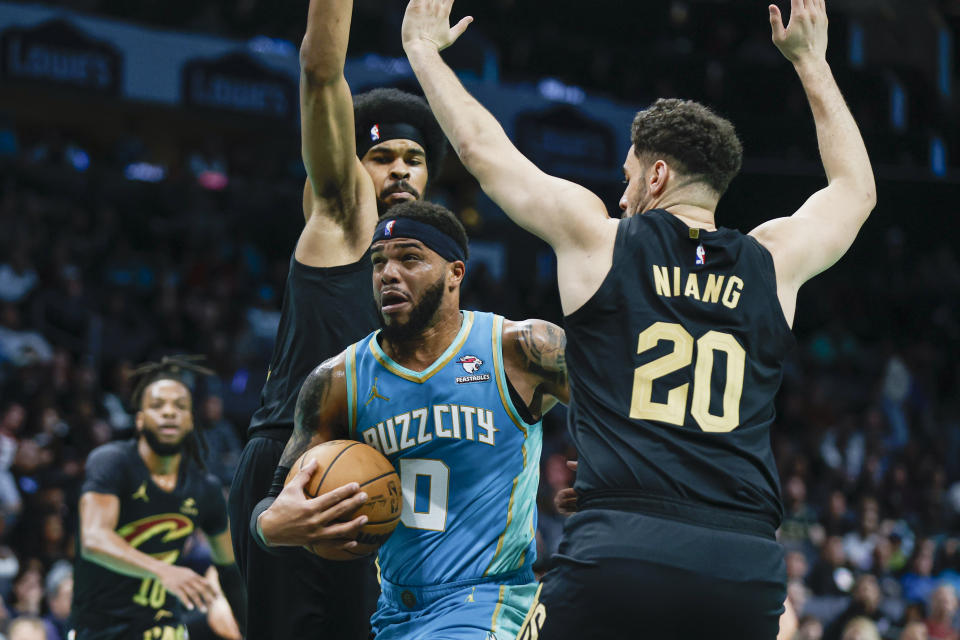 Charlotte Hornets forward Miles Bridges, center, drives between Cleveland Cavaliers center Jarrett Allen, left, and forward Georges Niang (20) during the first half of an NBA basketball game in Charlotte, N.C., Wednesday, March 27, 2024. (AP Photo/Nell Redmond)