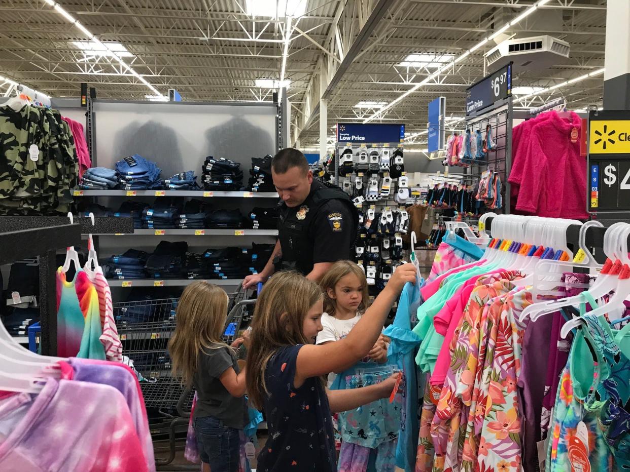 Mansfield police Officer Mark Boggs hands out police badge stickers to kids during Cops N Kids last August at Walmart on Possum Run Road during the 25th annual shopping event. The Mansfield Division of Police announced this week that Boggs was named 2021 Officer of the Year.