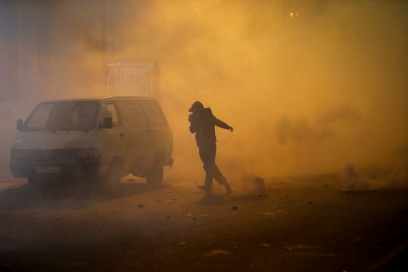 A demonstrator runs as the smoke rises during a protest against a ruling elite accused of steering Lebanon towards economic crisis in Beirut