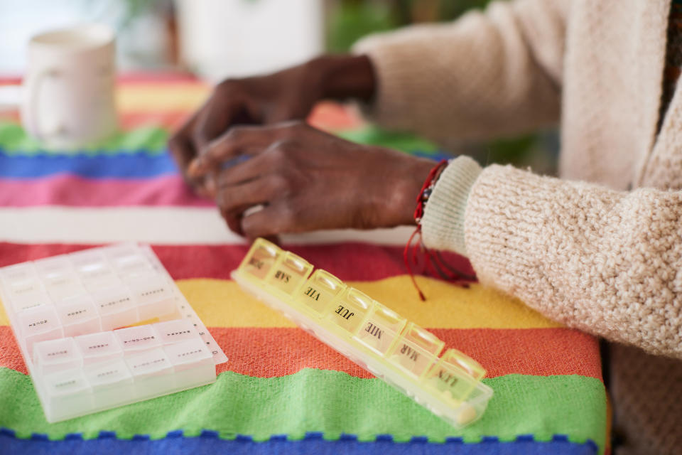 Person organizing medication into a labeled pill organizer on a table