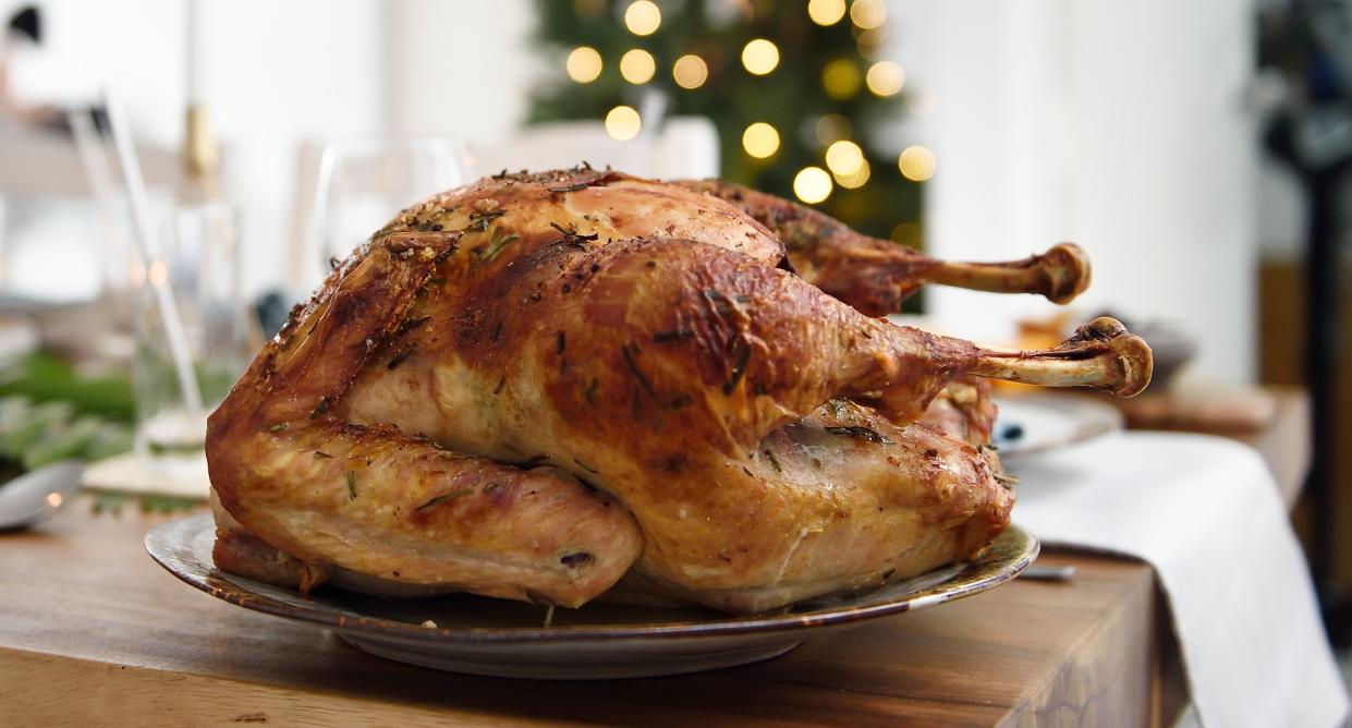 A roast turkey sits on a table with a Christmas tree in the background. (Getty Images)