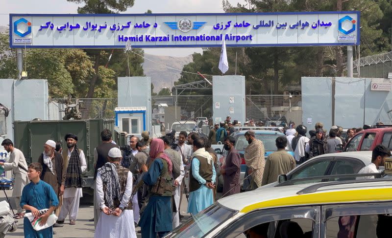 People gather at the entrance gate of Hamid Karzai International Airport a day after U.S troops withdrawal, in Kabul