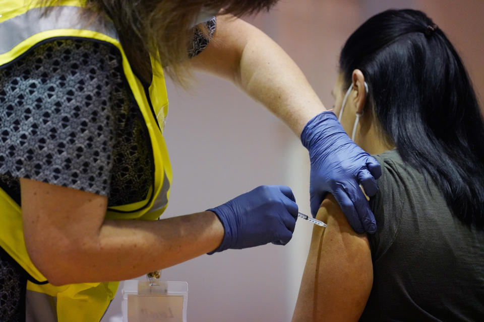 FILE - In this Tuesday, Jan. 5, 2021, file photo, a woman receives a dose of the COVID-19 vaccine from a pharmacist at Nassau County's first vaccination distribution site, set up by Northwell Health and Nassau County, at Nassau County Community College, in Garden City, N.Y. Vaccine passports being developed to verify COVID-19 immunization status and allow inoculated people to more freely travel, shop and dine have become the latest flash point in America’s perpetual political wars. (AP Photo/Kathy Willens, File)