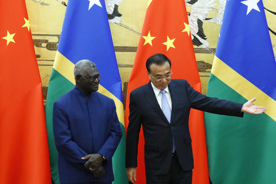 FILE - Chinese Premier Li Keqiang shows the way to Solomon Islands Prime Minister Manasseh Sogavare, left, as they attend a signing ceremony at the Great Hall of the People in Beijing on Oct. 9, 2019. China’s Foreign Minister Wang Yi is visiting the South Pacific with a 20-person delegation this week in a display of Beijing's growing military and diplomatic presence in the region. (Thomas Peter/Pool Photo via AP, File)