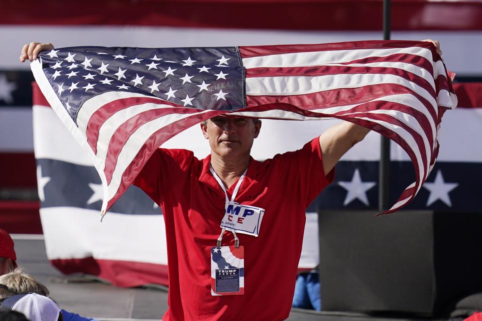 A supporter of President Donald Trump waves the American flag waiting for the arrival of Trump for a campaign rally Monday, Oct. 19, 2020, in Tucson, Ariz. (AP Photo/Ross D. Franklin)