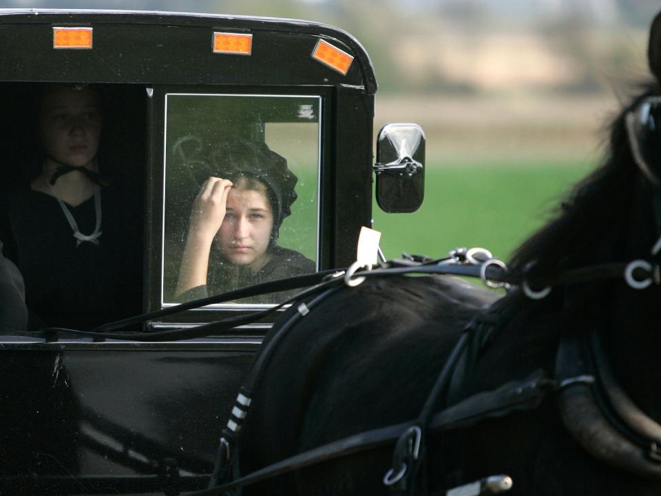 A young Amish girl looks out of a buggy window while participating in a funeral procession for one of the Miller girls October 5, 2006 in Nickel Mines, Pennsylvania.