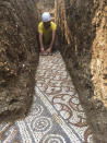 A man cleans a well-preserved colorful mosaic floor of an ancient Roman villa archaeologists have revealed among vineyards near the northern city of Verona, Italy. The official in charge of archaeology Verona province, Gianni de Zuccato, on Friday said the mosaics appeared to be ‘’in a good state of conservation,’’ from what they are able to observe after gingerly digging a trench between vineyards in the hills of Valpolicella, known for its full-bodied red wine. (Soprintendenza ABAP Verona via AP)