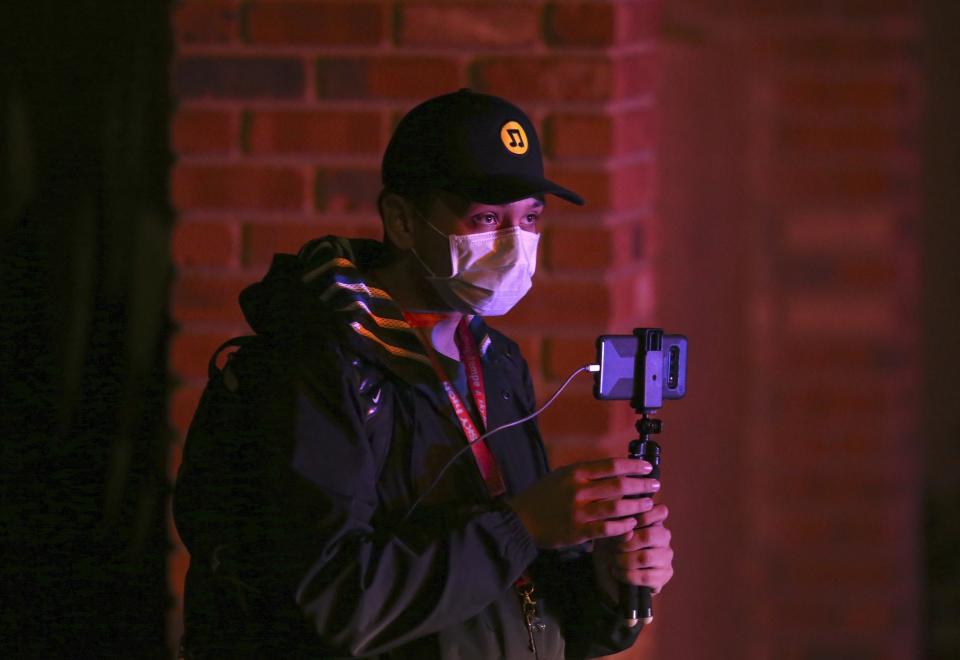 A nearby resident shoots video of a deadly shooting scene involving Phoenix Police officers in Phoenix, Ariz., Sunday, March 29, 2020. At least three Phoenix police officers were shot Sunday night on the city's north side, authorities said. (AP Photo/Ross D. Franklin)