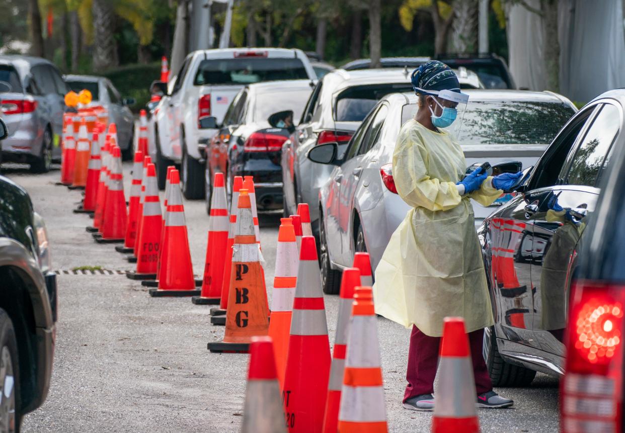 A healthcare worker gets information from peopled lined up to be tested at a COVID-19 testing site outside the Gardens Branch Library in Palm Beach Gardens, Florida on December 20, 2021.