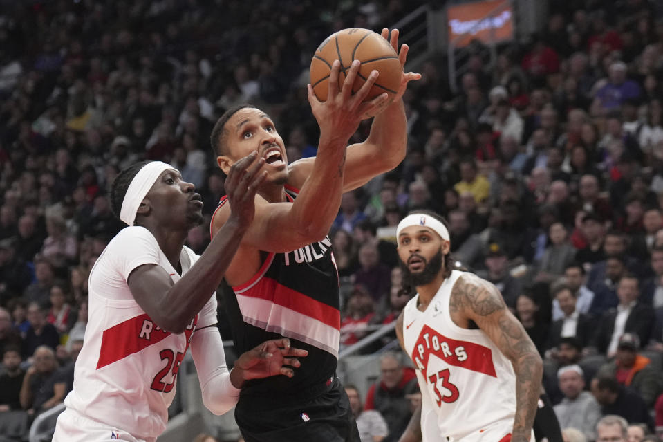 Portland Trail Blazers guard Malcolm Brogdon, center, drives to the net as Toronto Raptors forward Chris Boucher (25) defends during second-half NBA basketball game action in Toronto, Monday, Oct. 30, 2023. (Nathan Denette/The Canadian Press via AP)