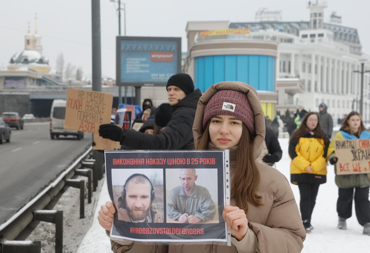 A woman holds up pictures of a captured relative during a demonstration calling for authorities to return their relatives from Russian captivity. (EPA)