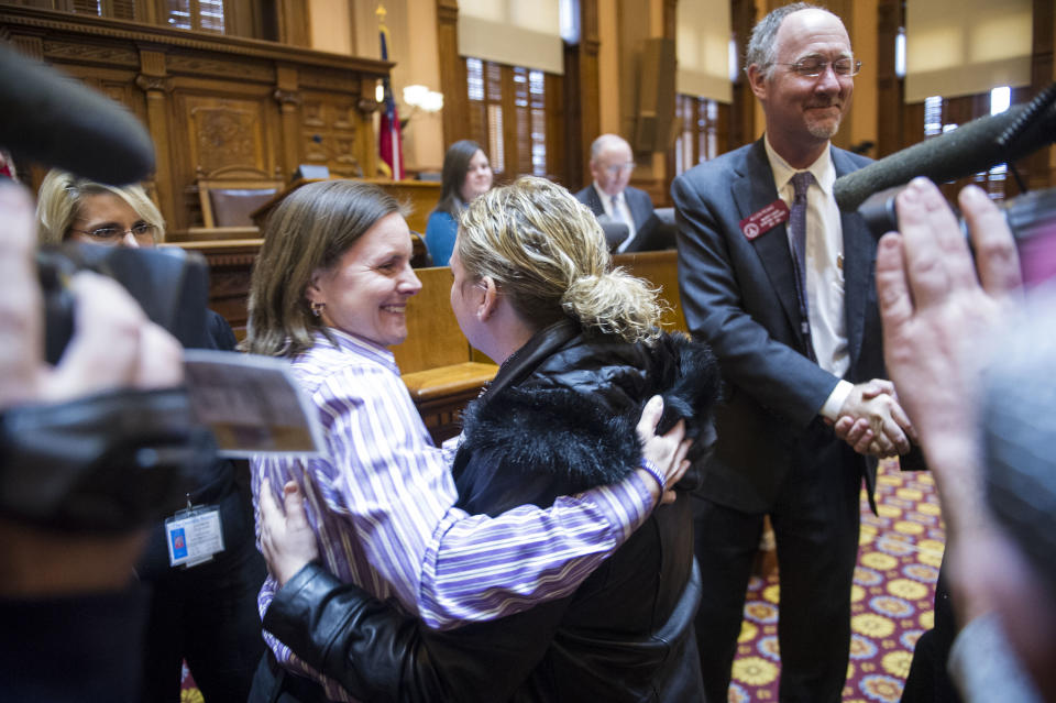 FILE - In a Tuesday, Jan. 28, 2014 file photo, medical marijuana advocates Shannon Cloud, left, from Smyrna, Ga., hugs Corey Lowe, as Rep. Allen Peake, R-Macon, right, receives a congratulatory handshake after he introduced a bill to legalize medicinal marijuana after a Georgia Legislative session in the House chamber, in Atlanta. Both Cloud and Lowe have children suffering from disease and believe marijuana can help relieve their pain. In states where lawmakers are more likely to talk about the importance of Second Amendment rights and displays of the Ten Commandments, there is a serious effort underway to legalize medical marijuana. The push is gaining momentum in the Deep South, due in large part to heart-breaking stories of children suffering dozens of seizures a day whose parents say they would benefit from access to a type of cannabis oil.(AP Photo/John Amis, File)