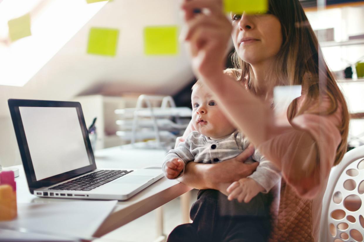 working mom at home with laptop and baby, organizing sticky notes