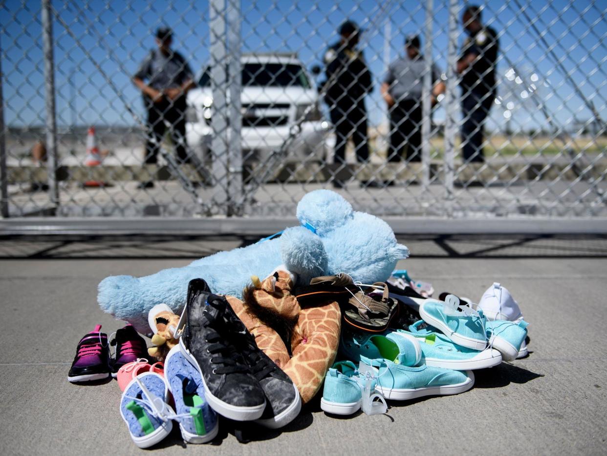 Security personnel stand before shoes and toys left at the Tornillo Port of Entry where children crossing the border without proper papers have been housed after being separated from adults: Brendan Smialowski/AFP via Getty Images