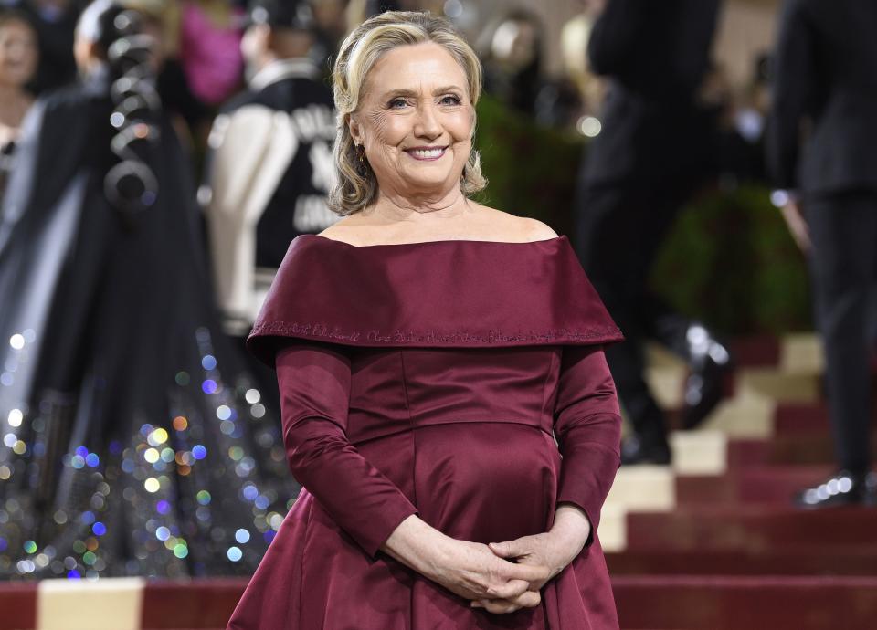 Hillary Clinton in maroon dress poses for photos