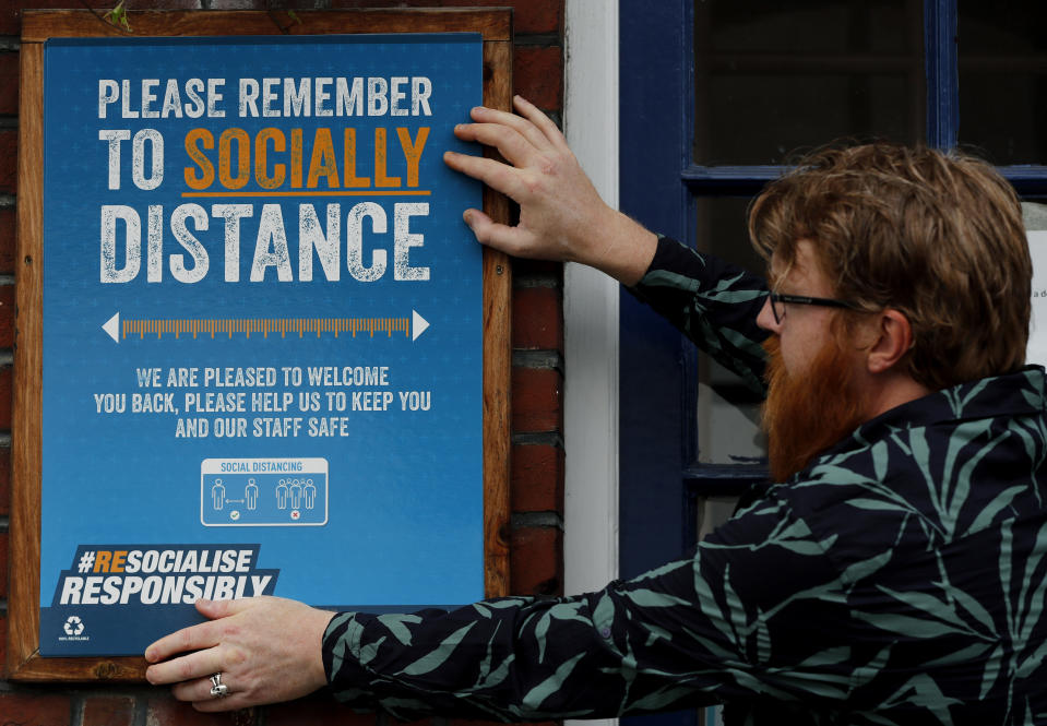 Owner Are Kjetil Kolltveit from Norway put signs in place instructing on social distancing at the Chandos Arms pub in London, Wednesday, July 1, 2020. Asking people in English pubs to keep their distance is going to be tough after they’ve had a few of their favorite tipples. Pub managers will have to be resourceful come Saturday, July 4, 2020, when they and other parts of the hospitality industry in England open their doors to customers for the first time since March 20, provided they meet COVID safety requirements. (AP Photo/Frank Augstein)