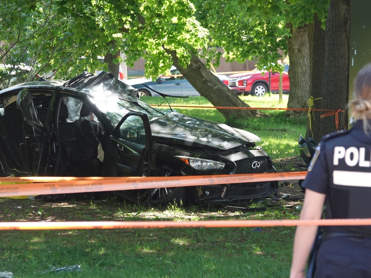 Police established a perimeter around the car crash site, blocking traffic on Côte Saint-Luc Road. The car was heavily damaged in the crash. (Benoit Gagnon/Radio-Canada - image credit)