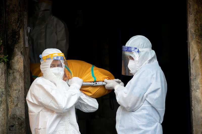 Volunteers wearing protective suits carry a body from a house amid the outbreak of the coronavirus disease in Yangon