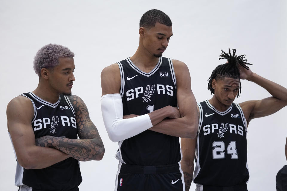 San Antonio Spurs center Victor Wembanyama, the NBA's first round draft pick, center, poses for photos with teammates Jeremy Sochan, left, and Devin Vassell, right, during an NBA basketball media day in San Antonio, Monday, Oct. 2, 2023. (AP Photo/Eric Gay)